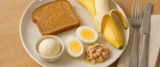 Military Diet meal with toast, banana, egg, tuna, and vanilla ice cream on a plate, arranged appetizingly on a wooden table