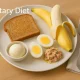 Military Diet meal with toast, banana, egg, tuna, and vanilla ice cream on a plate, arranged appetizingly on a wooden table