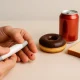 Blood sugar test from fingertip with visible drop, surrounded by unhealthy foods like doughnut, soda, and white bread for borderline diabetics