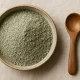 french green clay powder in ceramic bowl on linen background