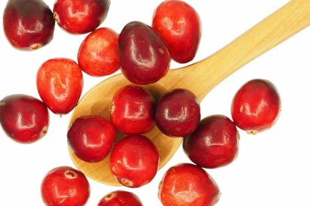 Ripe cranberries and a wooden spoon