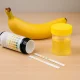 Home urine test strips with container and a banana on a wooden table, symbolizing diet effects and simple at-home diagnosis.