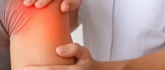 A close-up view of a physiotherapist performing passive range of motion (ROM) therapy on a male patient’s shoulder.