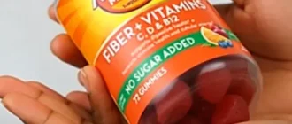 A woman is holding an orange Metamucil bottle in her hands