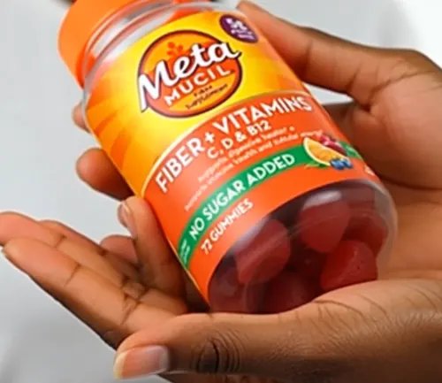 A woman is holding an orange Metamucil bottle in her hands